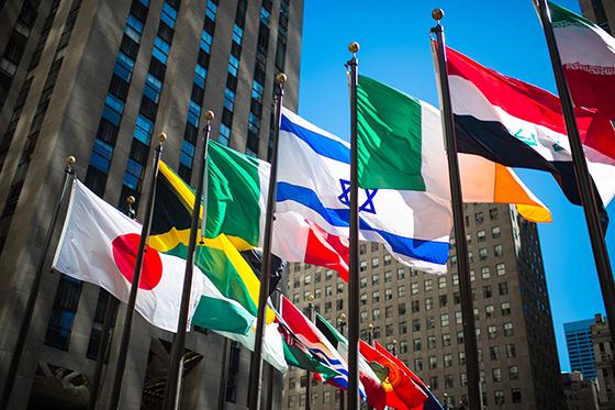Photo of flags of different nations flying in front of the United Nations building. 