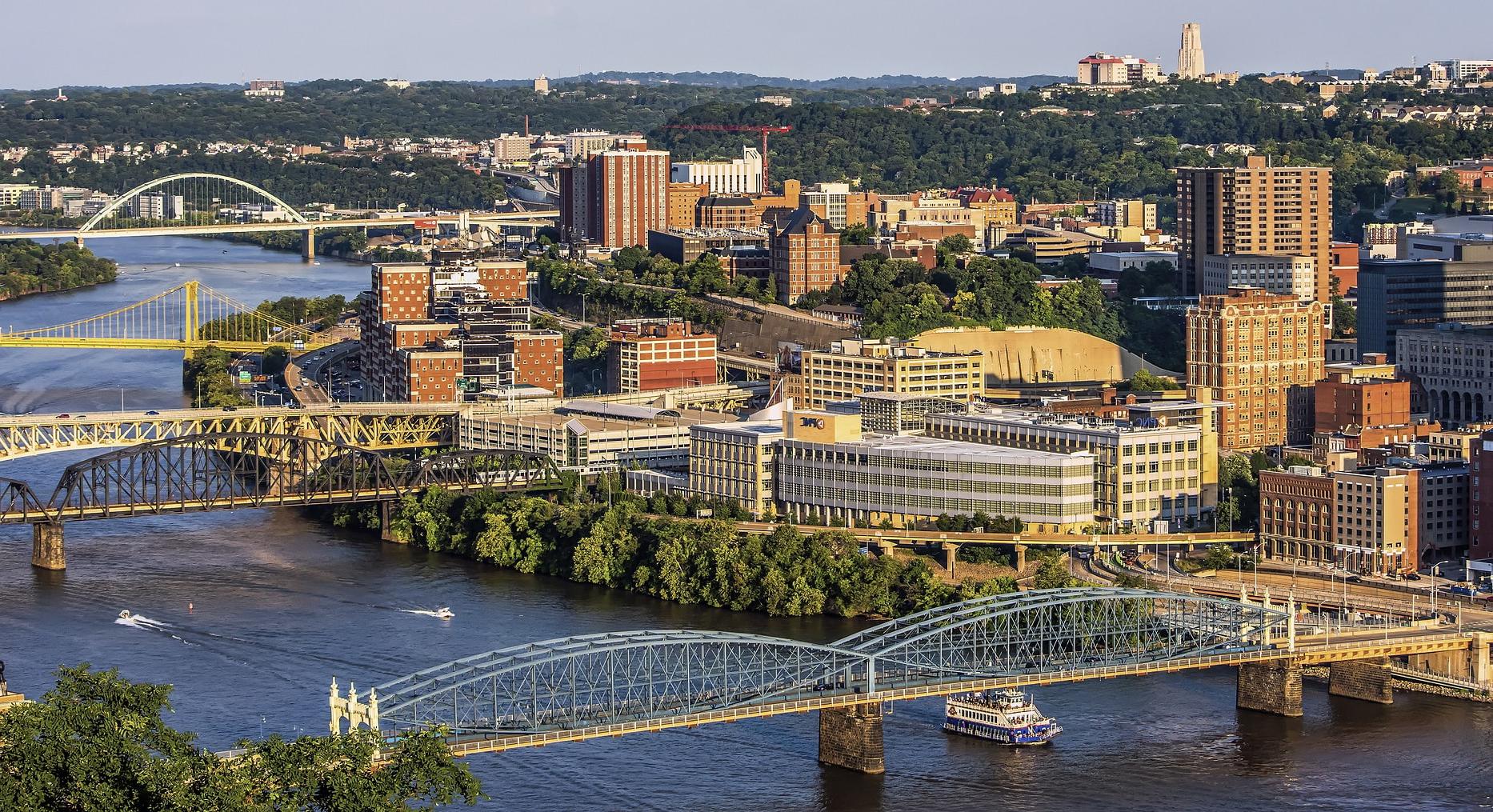 Photo of the Pittsburgh skyline with a river and yellow bridges