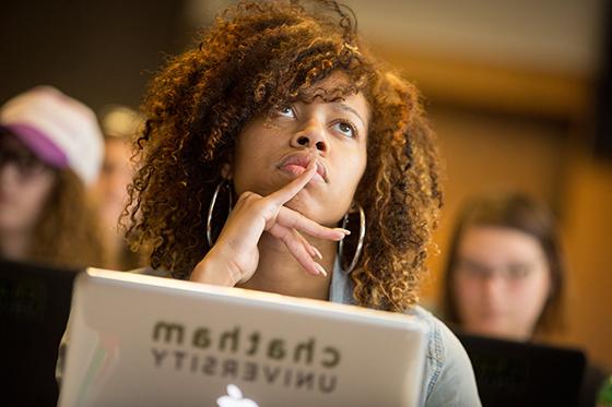 Photo of a female Chatham University student paying attention to a lecture, with a computer in front of her