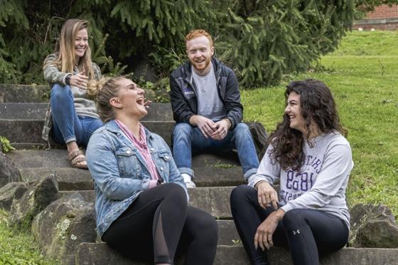Photo of four Chatham University students smiling and laughing together outside on Shadyside Campus