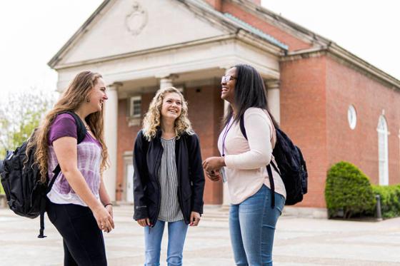 Photo of three Chatham University students on Shadyside Campus, talking and smiling outside
