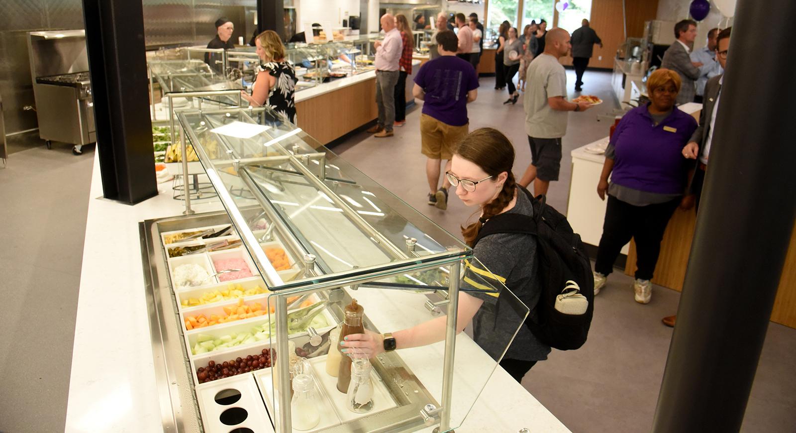 Photo of a student reaching for a condiment bottle at the salad bar in Anderson Dining Hall